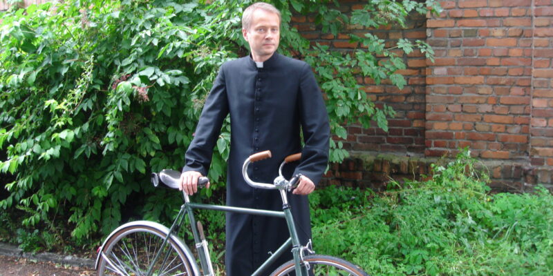 Ojciec Mateusz z nieodłącznym rowerem (fot. Baldmedia, Wikipedia)